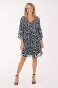A woman wearing a black and white 3/4 sleeve dress with a heart pattern.