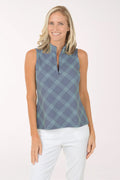 Woman wearing a sleeveless patterned top and white pants on a white background