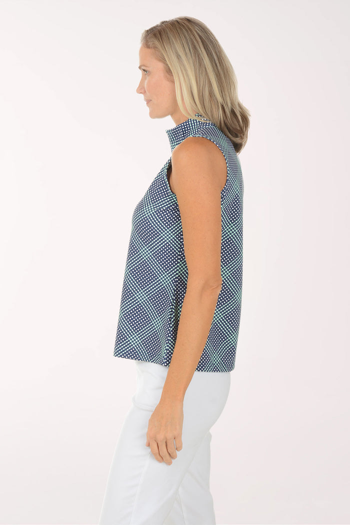 Woman wearing a sleeveless patterned top and white pants on a white background